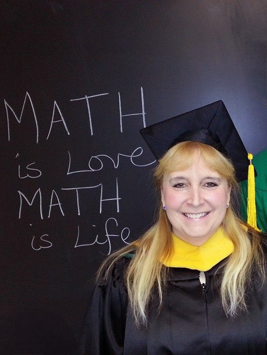 Hanni Nichols in graduation regalia, with the words "Math is love, math is life" written on a chalkboard