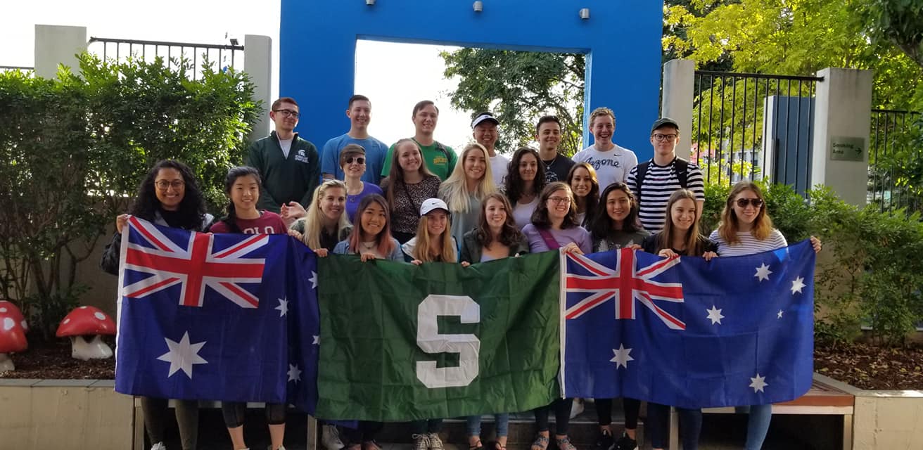 Students holding an Australian flag and an MSU flag in Brisbane, Queensland, Australia