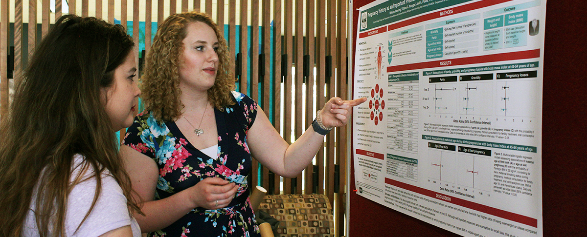 A student explains research findings at the Research Symposium