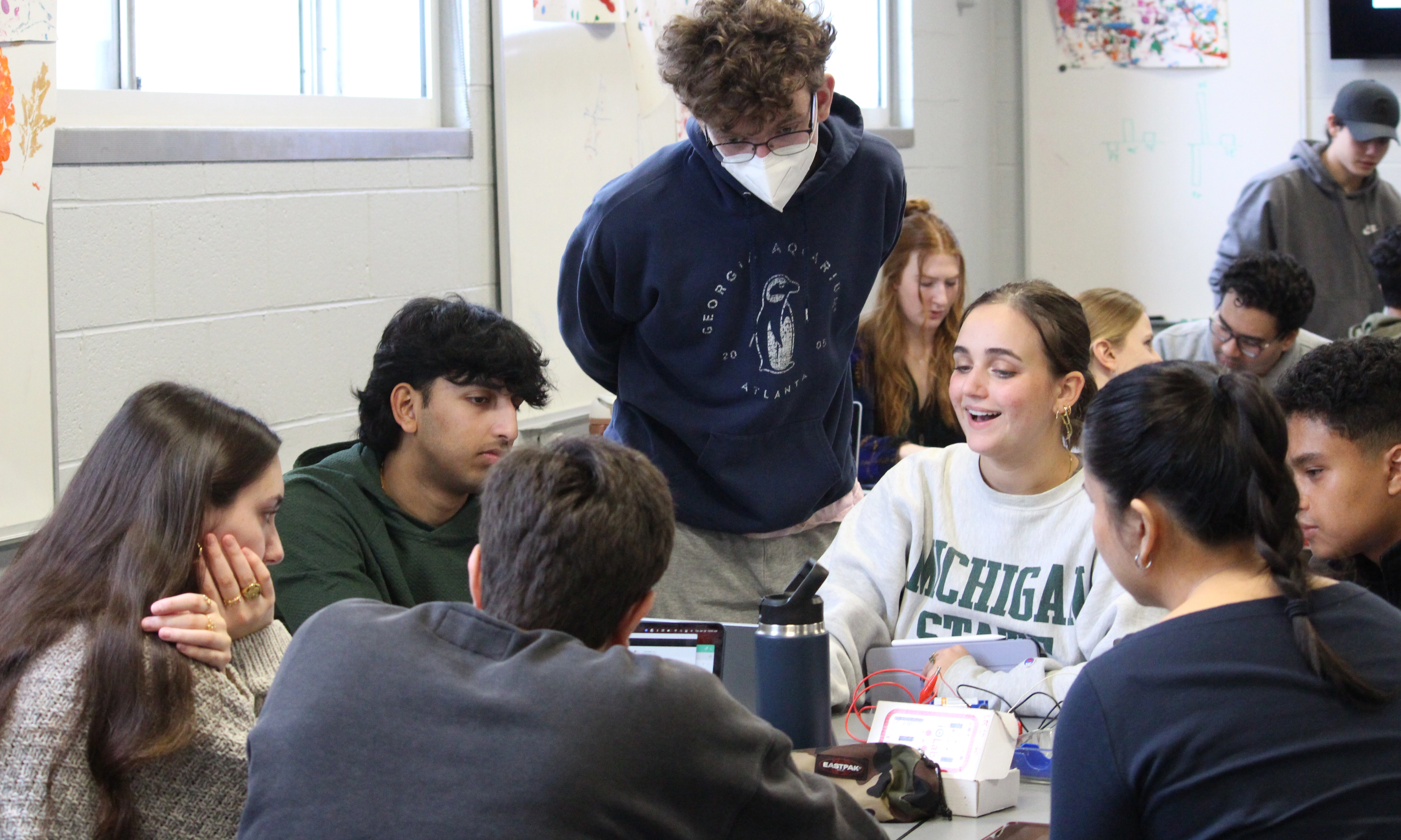 Group discussion in a physics classroom, with a learning assistant contributing