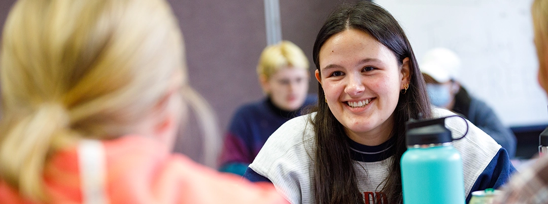 A student smiles at another in class