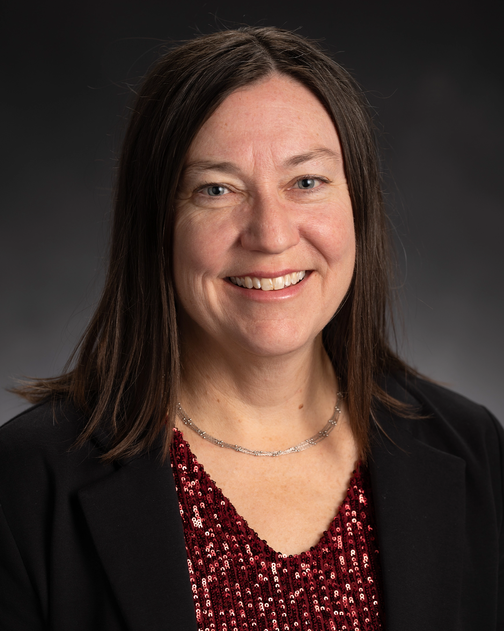 Dean Kendra Cheruvelil has long brown hair and wears a jacket and red top
