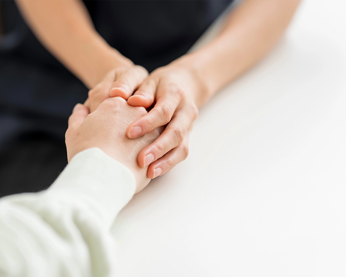 a person wearing black holds the hand of an older person, wearing white 