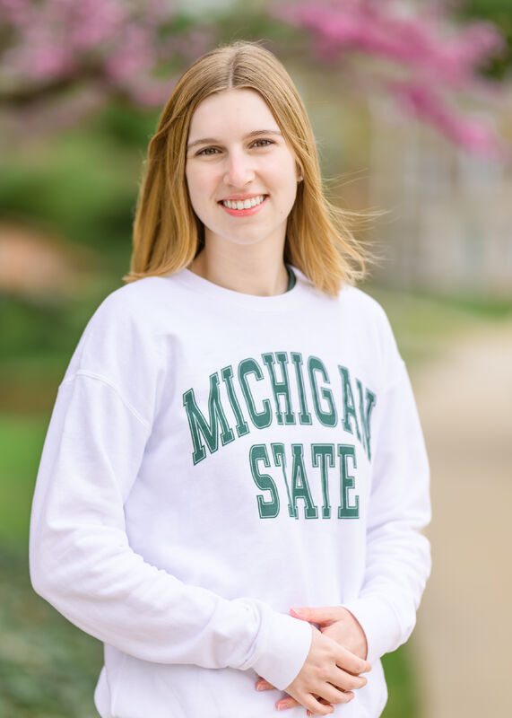 Caroline Beckrow, member of the 2025 Homecoming Court, smiles and wears a white MSU sweatshirt
