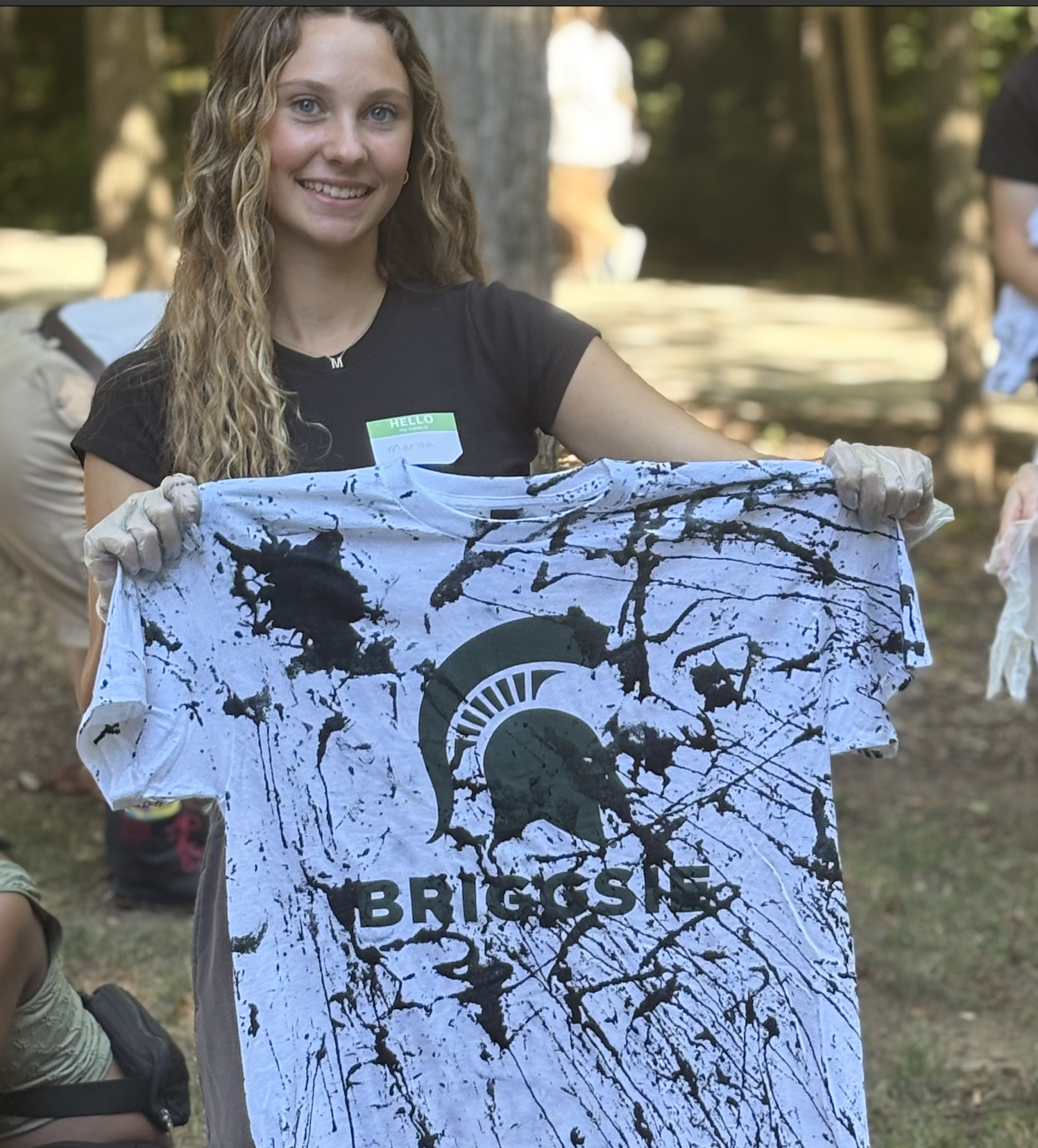 a student holds up a tie-dyed Briggsie t-shirt