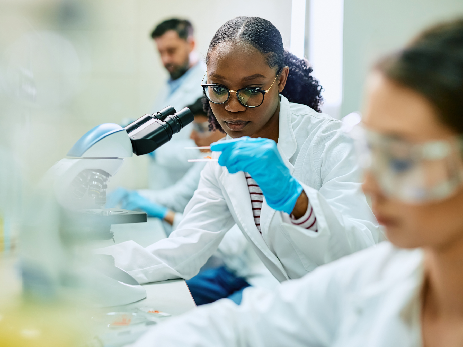A person works in a lab and focuses their attention on something on a slide
