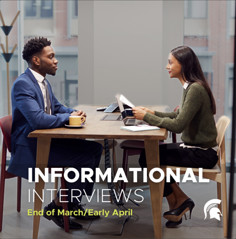 Two people sit across from one another. They are dressed professionally and it appears one is asking interview questions of the other