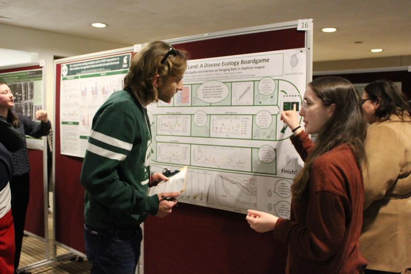 An LBC alum listens to a student presenting at the 2025 LBC Research Showcase
