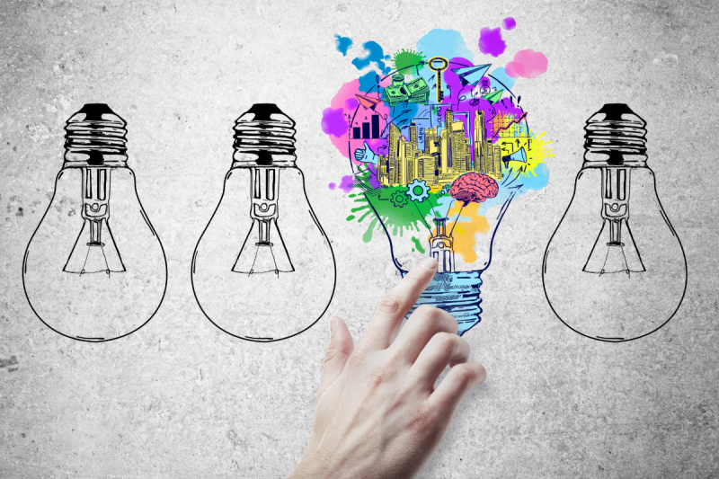 Graphic of a hand by sketches of upside down light bulbs. The finger is pointed to a light bulb facing the other way and full of color and images.