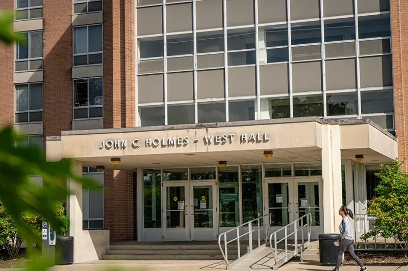 A student walks by the entrance of Holmes Hall