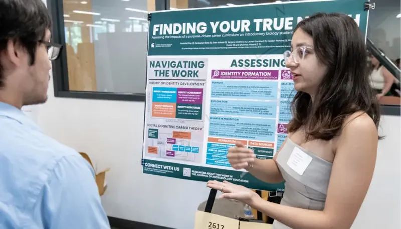Student discussing her research in front of poster