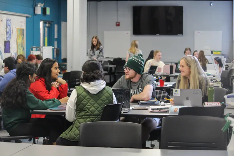 Students talking at a table in a studio physics classroom