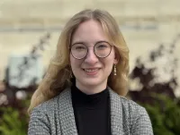 Kierra Jursch has blond, wavy hair and glasses. She is smiling and is wearing a checkered blazer and black turtleneck top. Courtesy photo