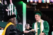 John Morrison receives his diploma from Dean Kendra Spence Chervuvelil