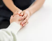 a person wearing black holds the hand of an older person, wearing white